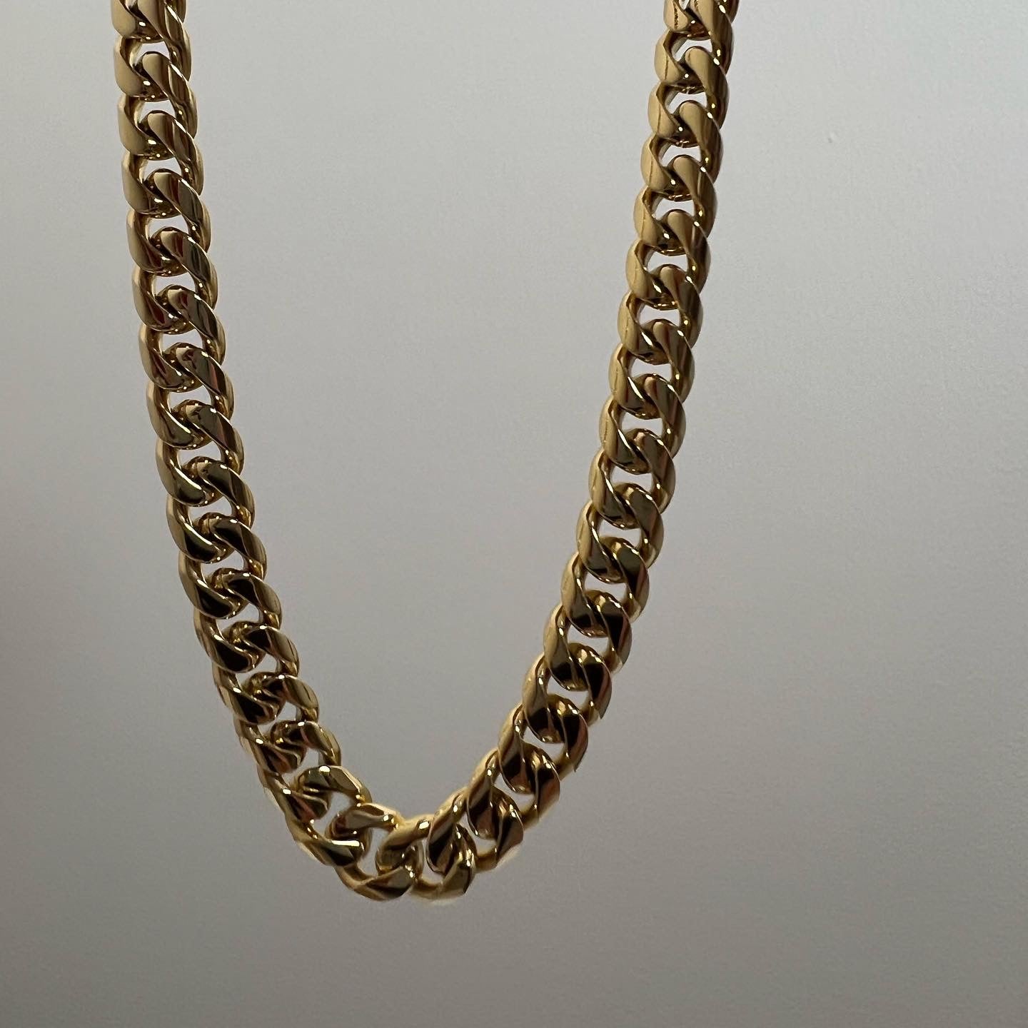 Gold 8mm Cuban Link Chain on marble background
