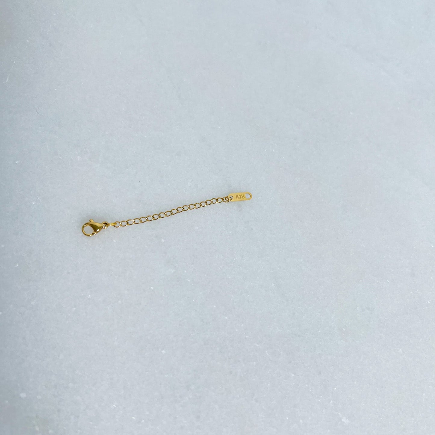 Gold extender chain on a light gray background