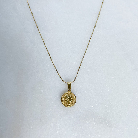 Gold necklace with a round pendant on a white background