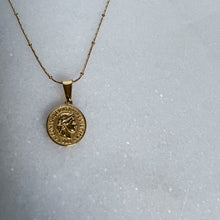 Load image into Gallery viewer, Gold necklace with a round pendant on a light gray background
