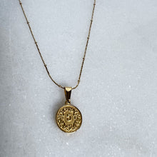Load image into Gallery viewer, Gold necklace with a circular pendant on a light gray background

