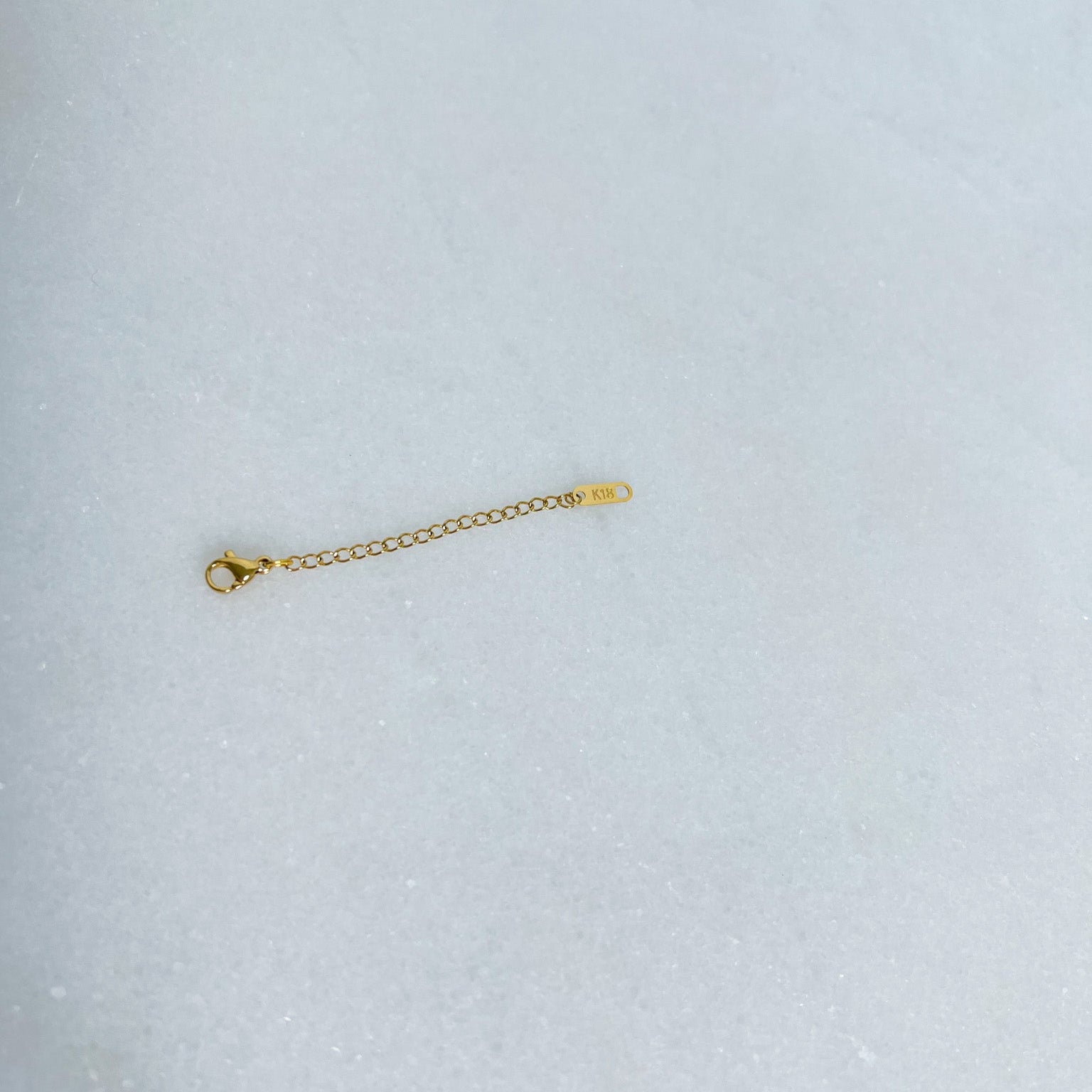 Gold extender chain on a light gray background