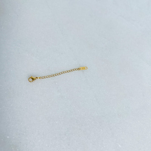 Gold extender chain on a light gray background