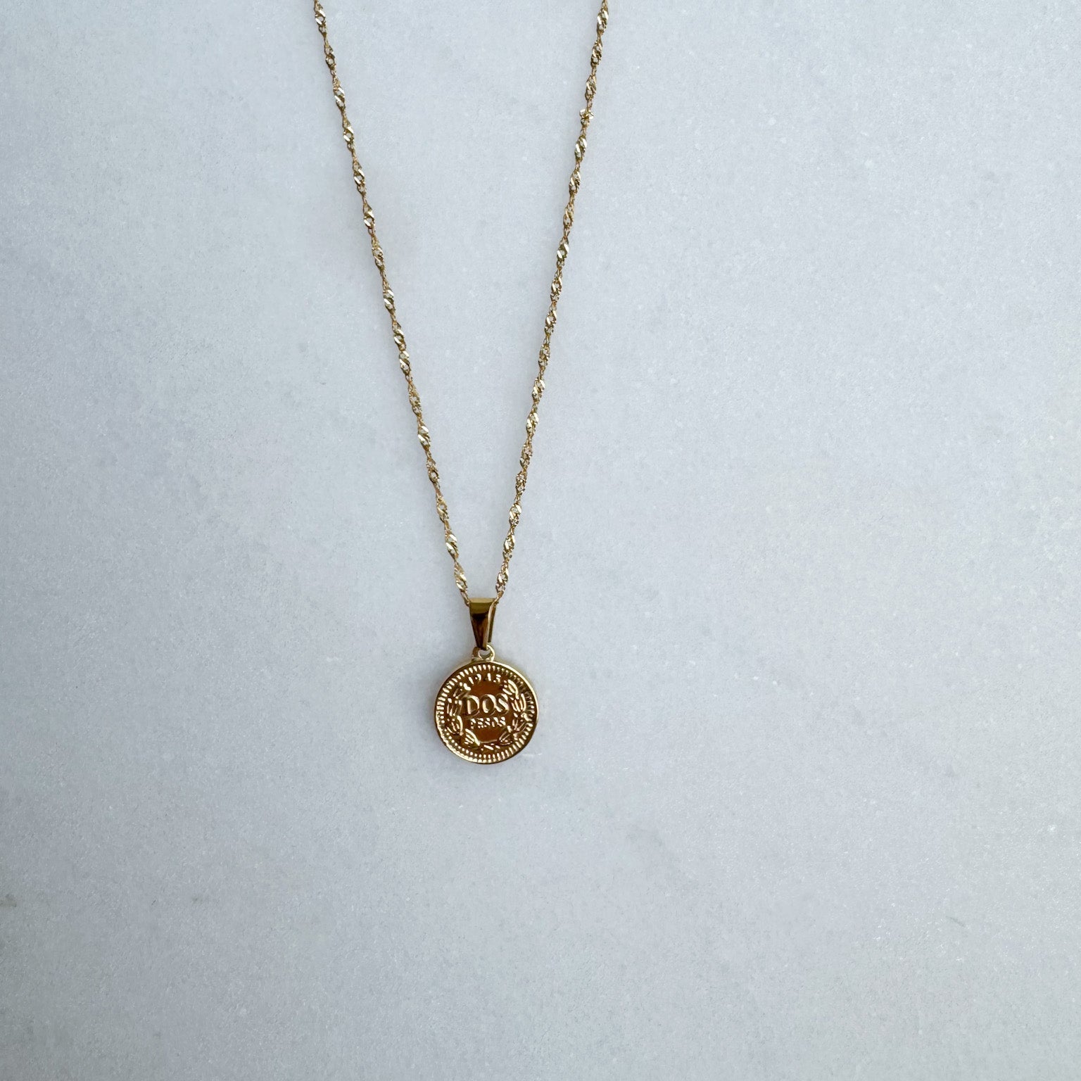 Gold necklace with a round pendant on a white surface