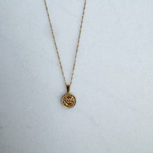 Load image into Gallery viewer, Gold necklace with a round pendant on a white surface

