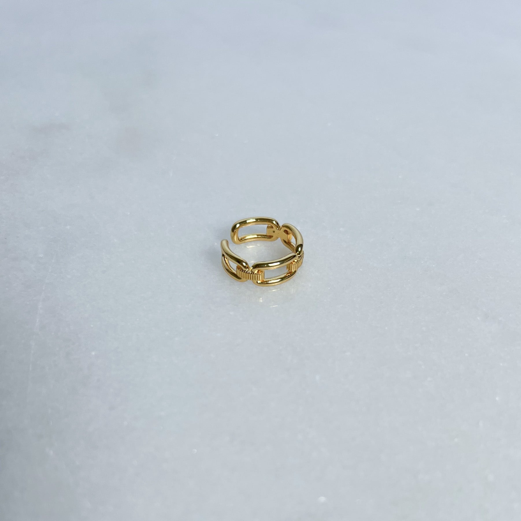 Gold link ring on a light gray background