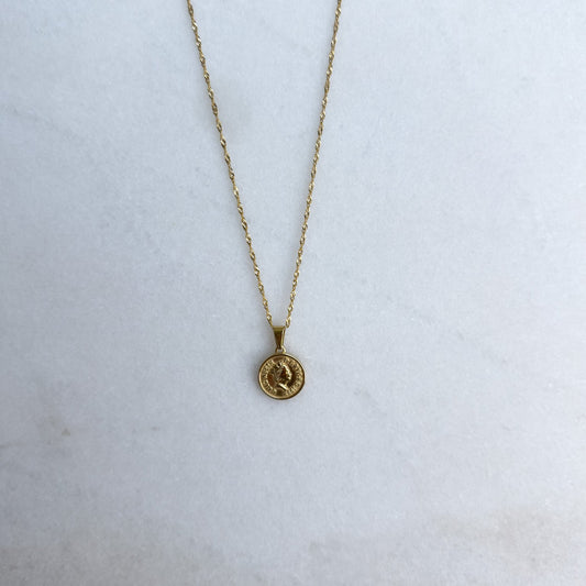 Gold necklace with a coin pendant on a white background