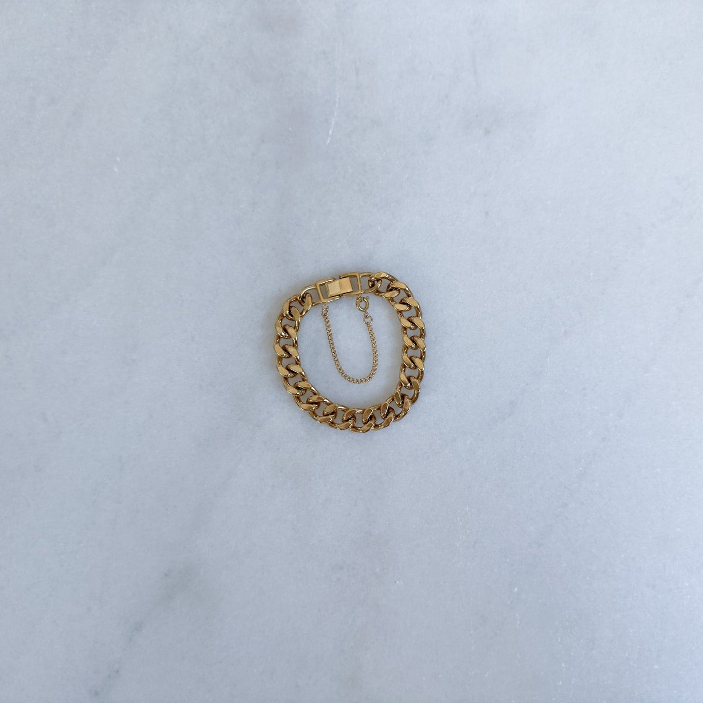 Gold chain bracelet on a light blue fabric background