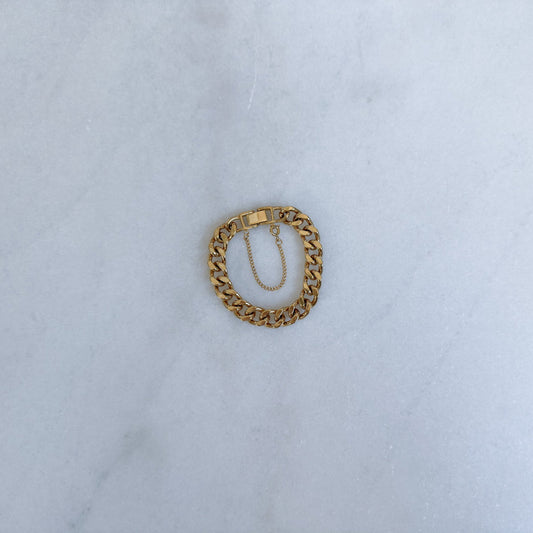 Gold chain bracelet on a light blue fabric background