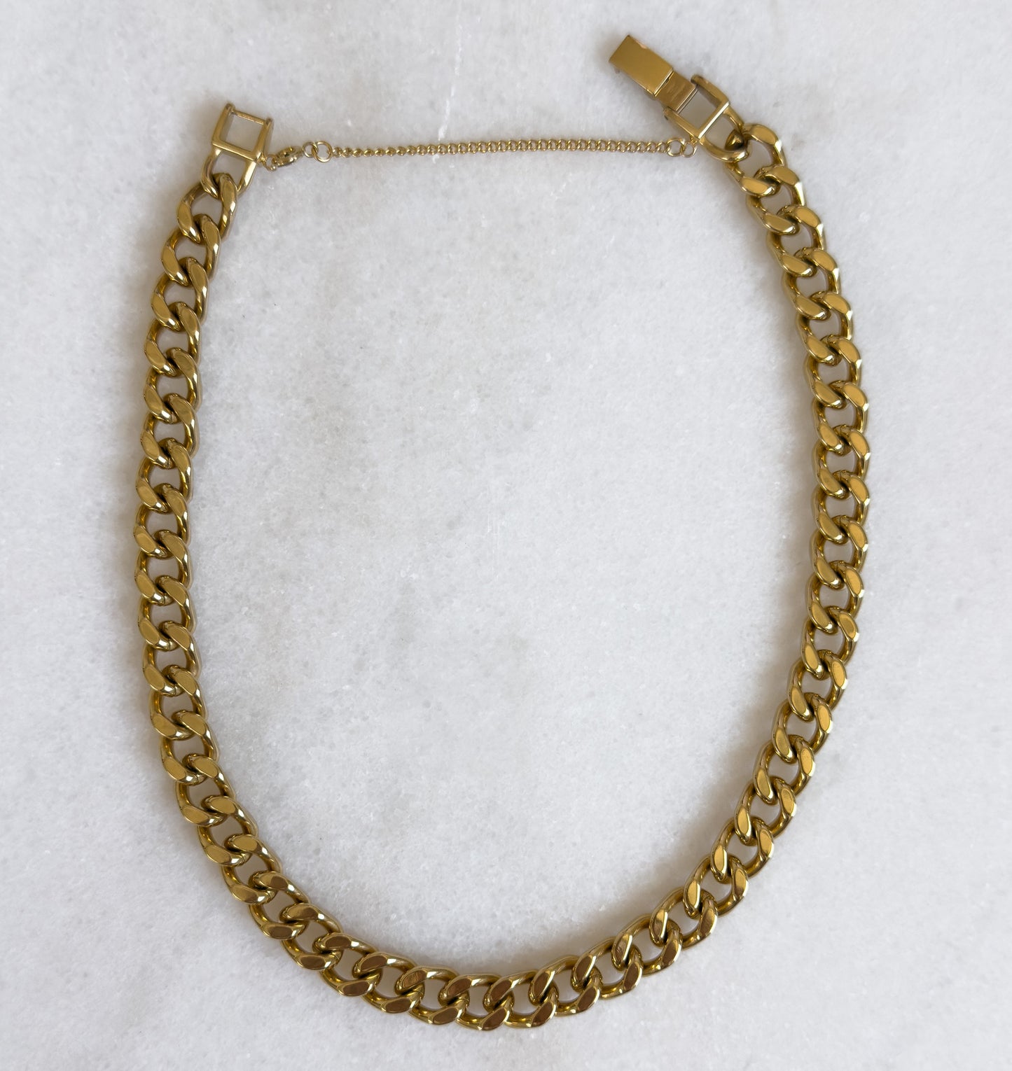Gold chain necklace on a white marble surface