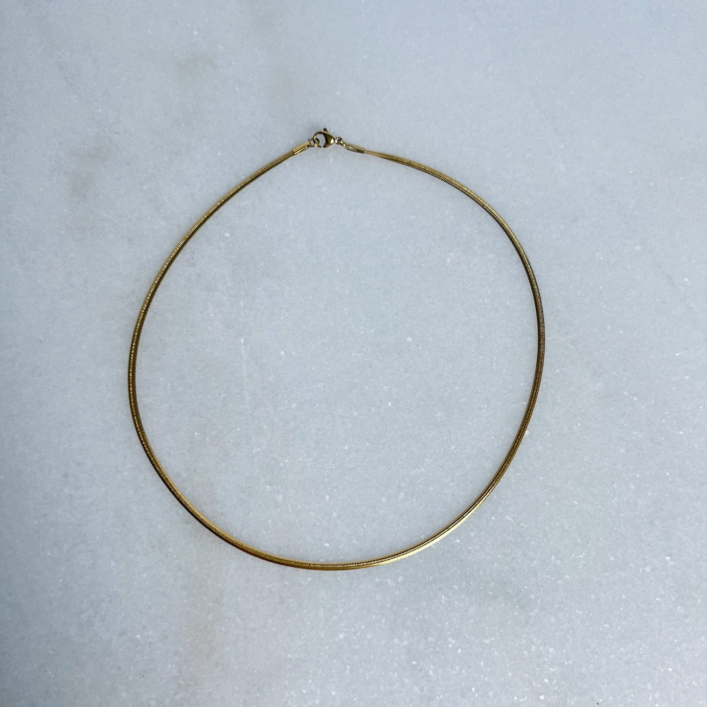 Gold herringbone necklace on a light gray background