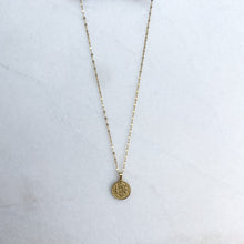 Load image into Gallery viewer, Gold necklace with a round pendant on a white background
