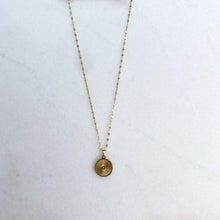 Load image into Gallery viewer, Gold necklace with a round pendant on a white surface
