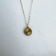 Load image into Gallery viewer, Gold necklace with a circular pendant on a light gray background
