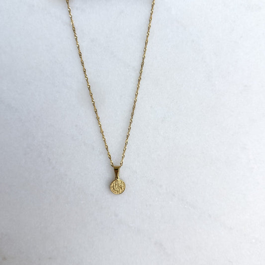 Gold necklace with a pendant on a white surface