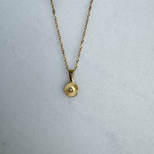 Load image into Gallery viewer, Gold necklace with a round pendant on a light gray background
