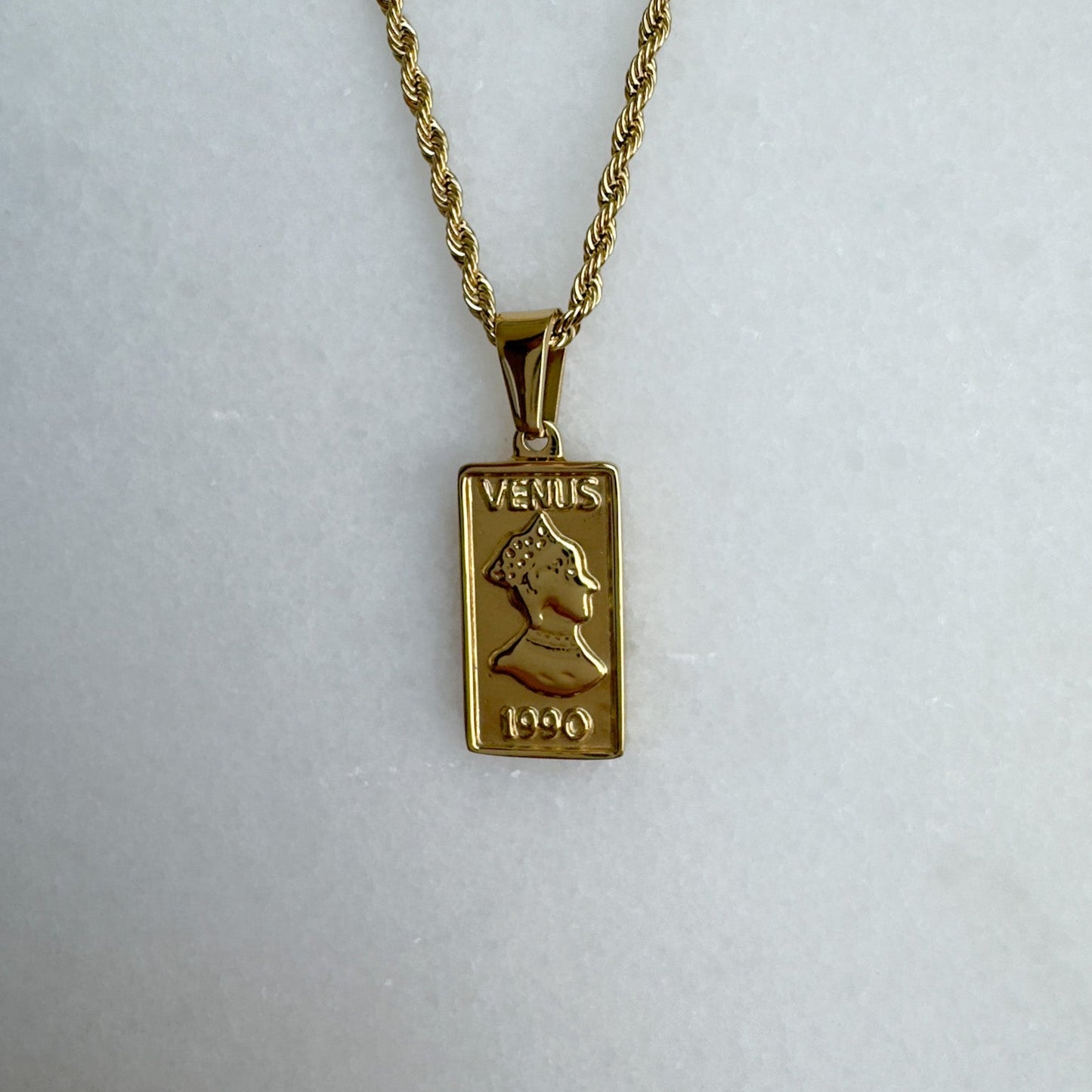 Gold necklace with a rectangle pendant on a white background