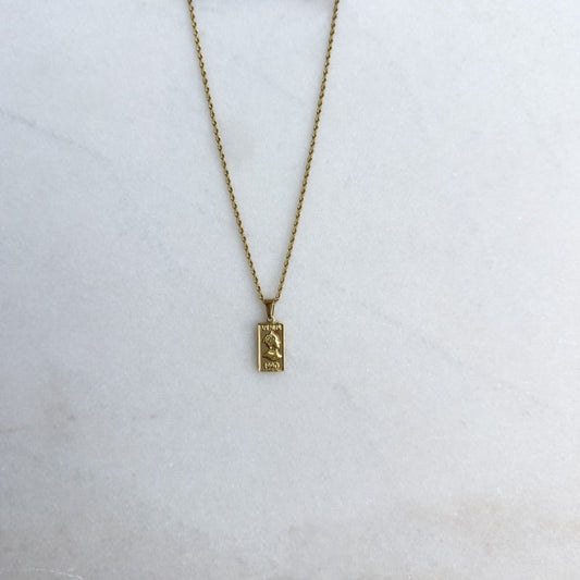 Gold necklace with a rectangle pendant on a white surface
