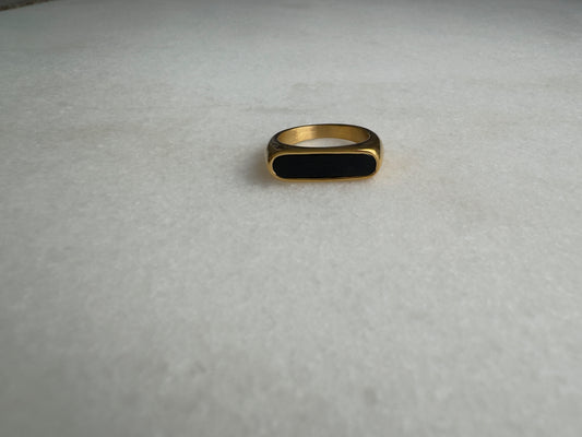 Gold signet ring with black enamel on marble background