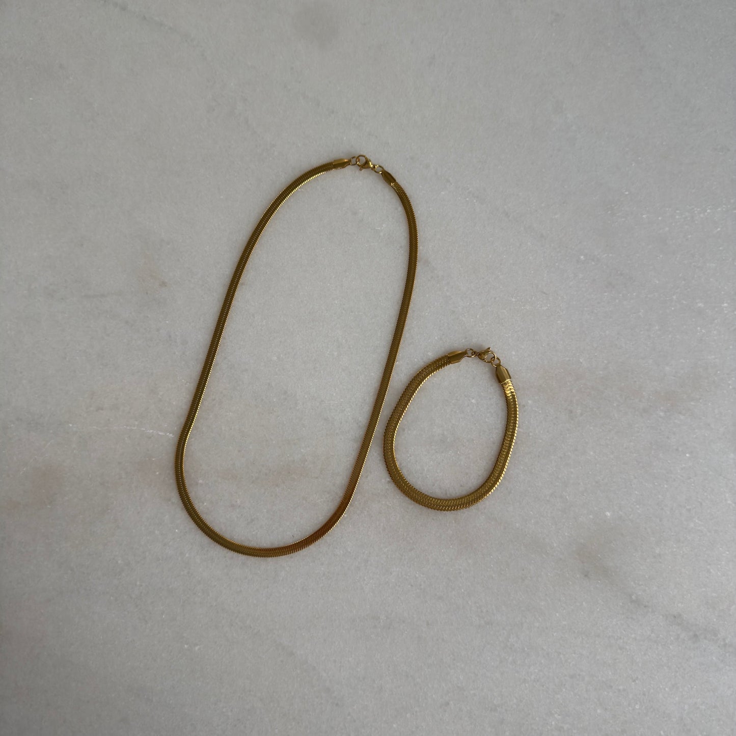 Gold Herringbone Bracelet on with matching necklace  marble background