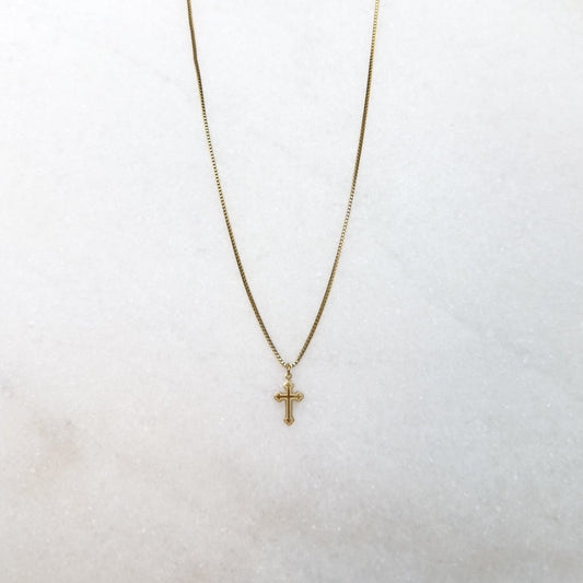 Gold necklace with a cross pendant on a white surface 