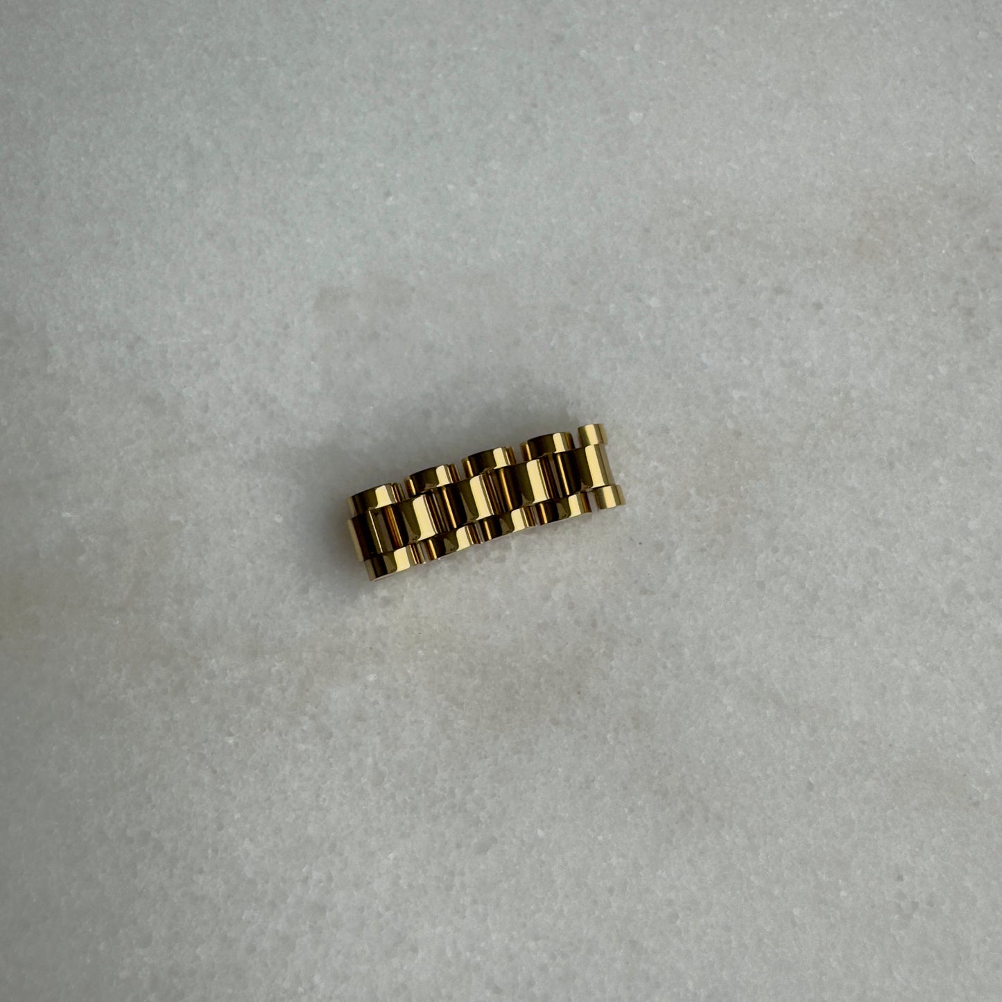 Gold watch link ring on marble background