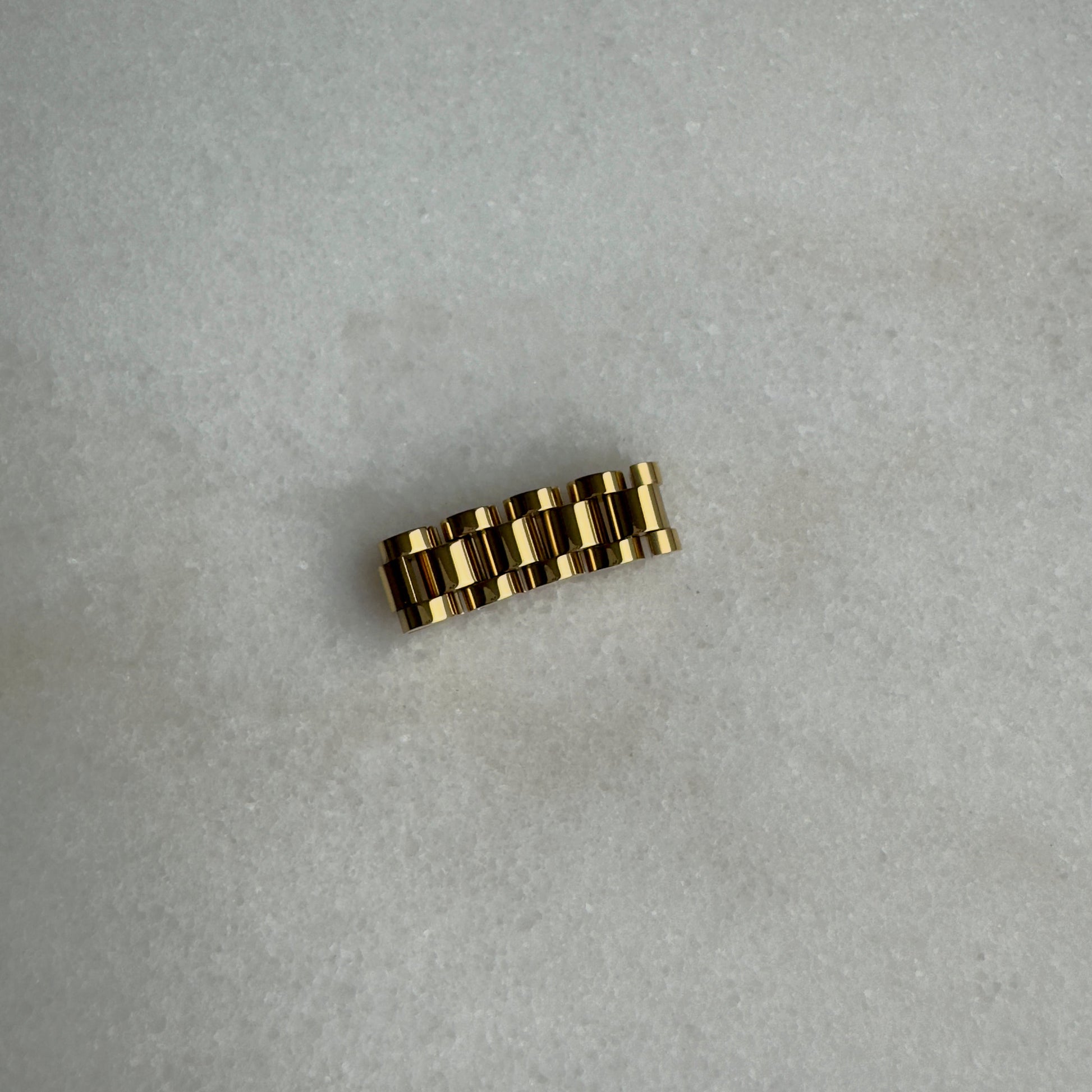 Gold watch link ring on marble background