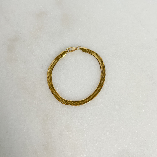 Gold Herringbone Bracelet on marble background