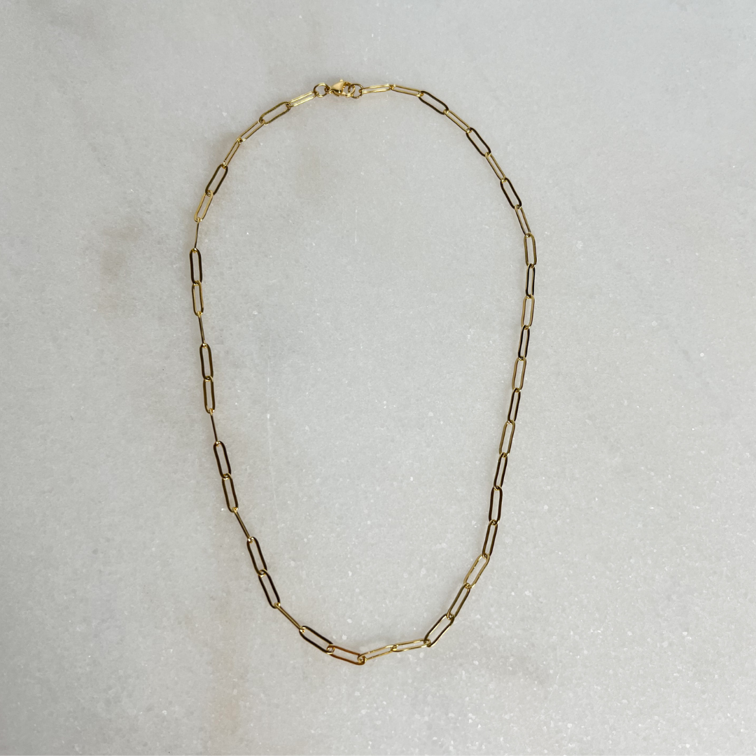 Gold Paperclip Necklace on marble background.