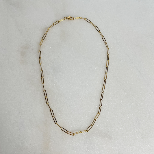 Gold Paperclip Necklace on marble background.