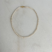 Load image into Gallery viewer, Pearl necklace with gold clasp on marble background.
