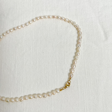 Load image into Gallery viewer, Pearl necklace with gold clasp on white linen background.

