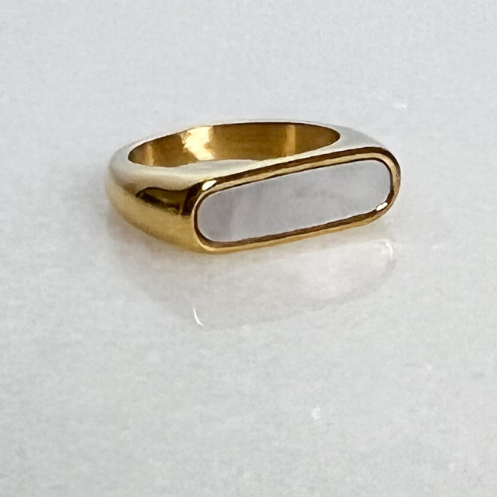 Gold signet ring with white enamel on marble background